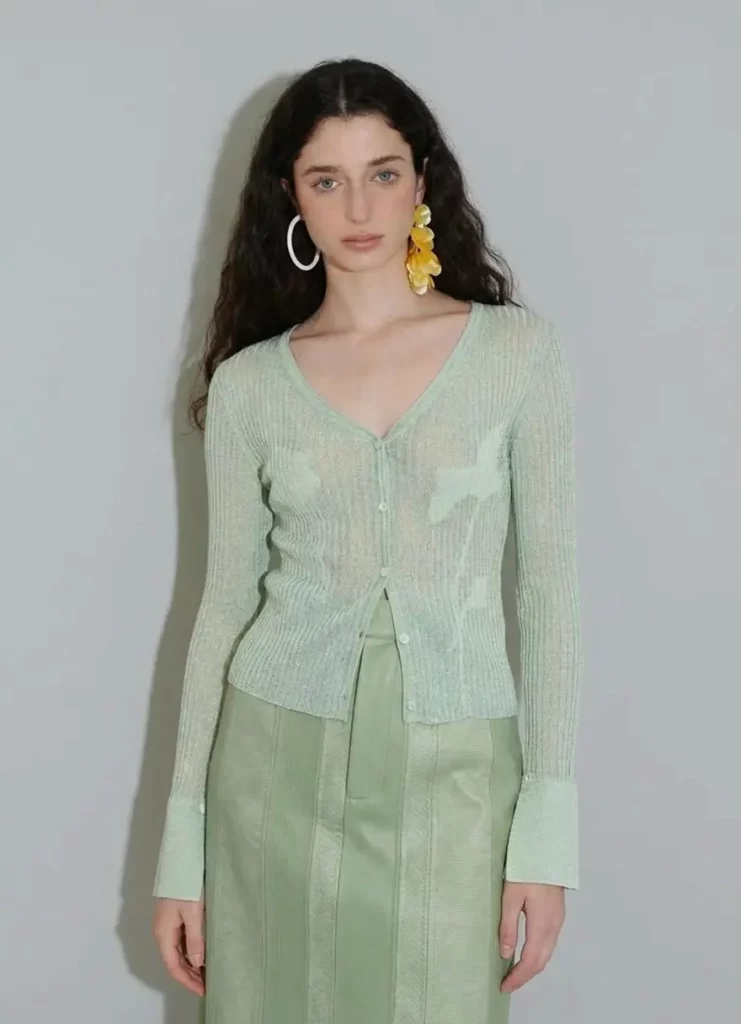 AI outfit change showing a pale green cardigan and matching skirt on the same model.