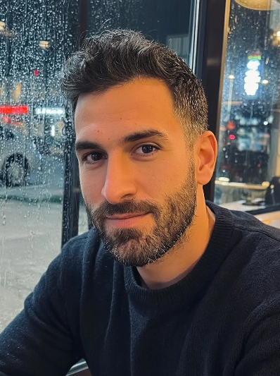 A handsome young man with dark hair and a trimmed beard looking at the camera, used as a base for a demon slayer oc maker transformation.