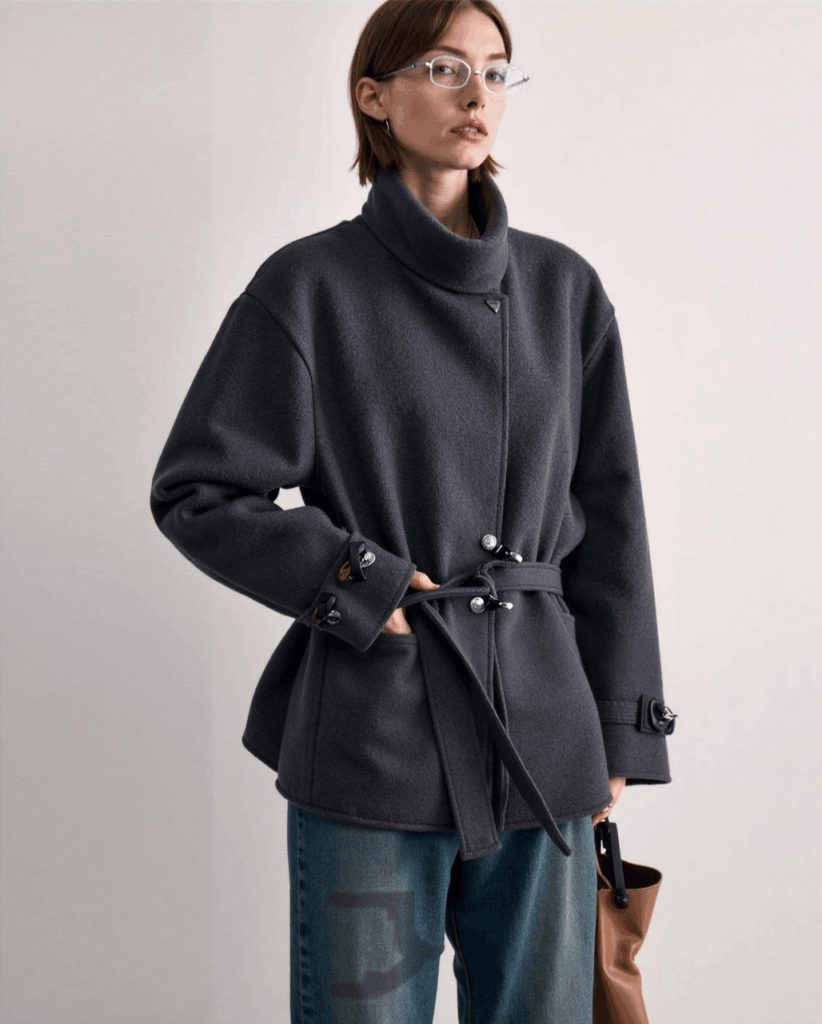 AI virtual try-on result showing a dark gray coat instead of the lavender fluffy reference coat, demonstrating color and garment deviation.