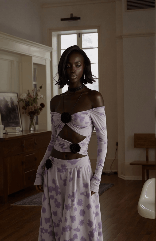 褐色肌膚的時尚模特兒穿著薰衣草花紋套裝，在柔和照明的室內環境中。