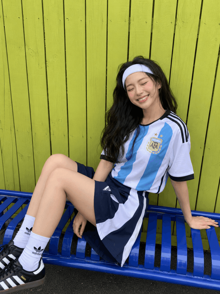cup4 – WeShop AI Blog Sporty chic football outfit with an Argentina-style jersey, casual shorts, sneakers, and a headband, showing an easy World Cup fashion look.