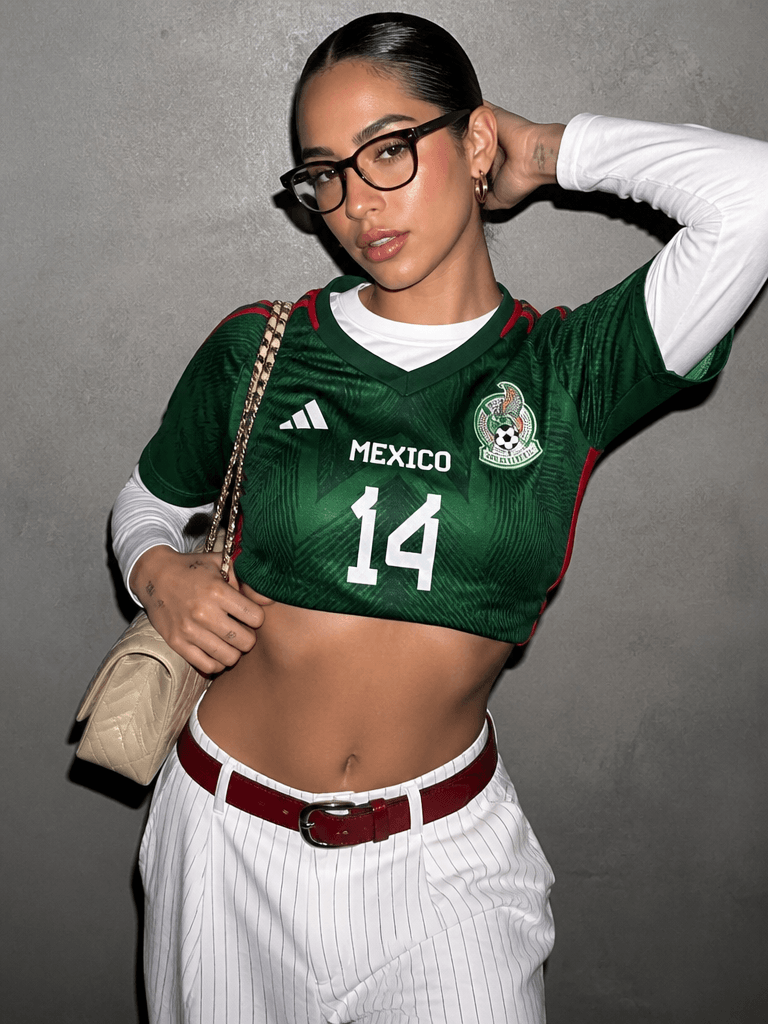 cup5 – WeShop AI Blog Y2K football fashion look with a green jersey, layered white top, glasses, chain bag, striped pants, and bold styling for young social media audiences.