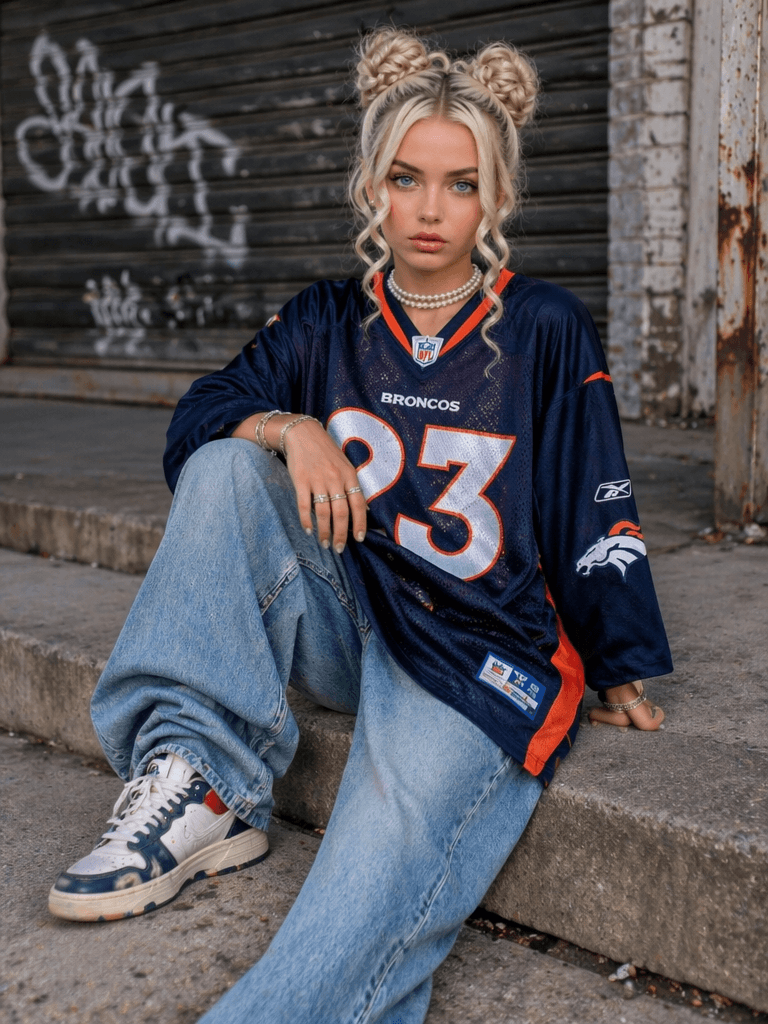 球衣6 – WeShop AI Blog Blonde woman wearing an oversized navy football jersey with baggy jeans and sneakers while sitting on urban concrete steps