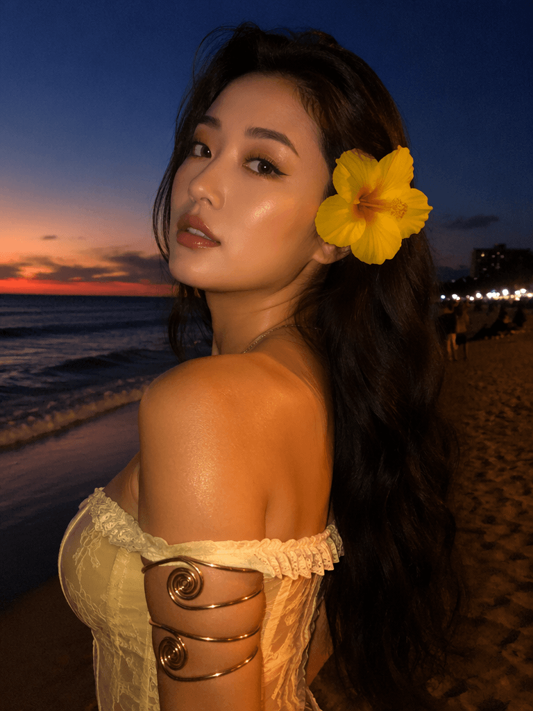球衣7 – WeShop AI Blog Woman posing at sunset on the beach with a yellow flower in her hair and a soft romantic vacation fashion look