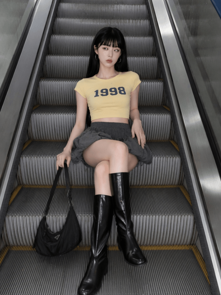 电梯 – WeShop AI Blog AI fashion model sitting on an escalator in a yellow crop top and black boots for an AI escalator video