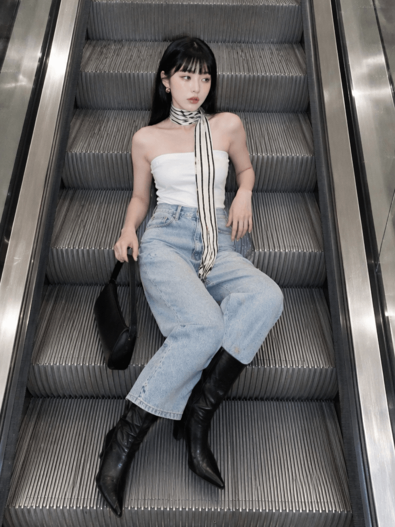 电梯2 – WeShop AI Blog AI model sitting on an escalator in a white top and light blue jeans for an AI fashion video concept