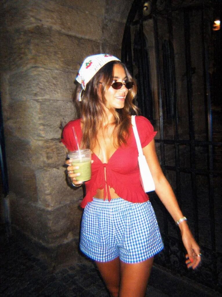 Retro disposable camera style edit of a woman in a red top with strong flash, deep shadows, grain, and early 2000s color.