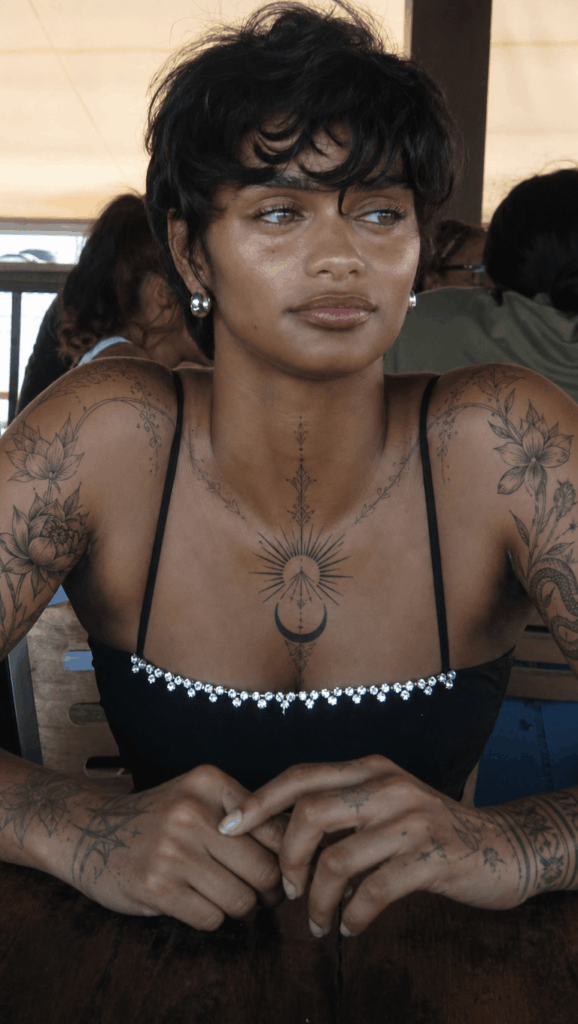 纹身4 – WeShop AI Blog Woman with AI-generated floral and ornamental tattoos across her shoulders, arms, chest, and neckline.