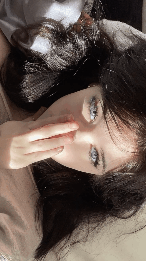赛博33 – WeShop AI Blog Original portrait of a dark-haired woman covering part of her face with her hand, used for an AI anime portrait transformation.