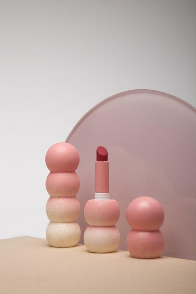 67e68c87ec14fa0372d155de_original – WeShop AI Blog AI Product Photography showing minimalist pink cosmetic products against a simple neutral studio background.