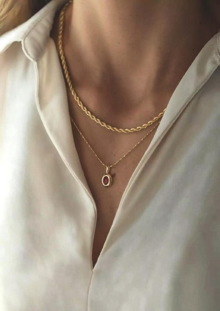 68d65c49c932c87fc7d9c597_final – WeShop AI Blog Layered gold necklaces over a white shirt after AI Relight with brighter highlights and clearer fabric detail.