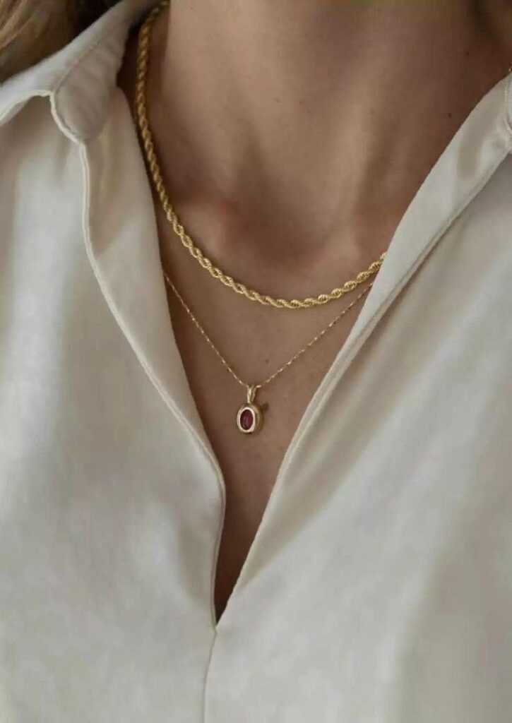68d65c49c932c87fc7d9c597_original – WeShop AI Blog Layered gold necklaces over a white shirt before AI Relight with softer, dimmer lighting.