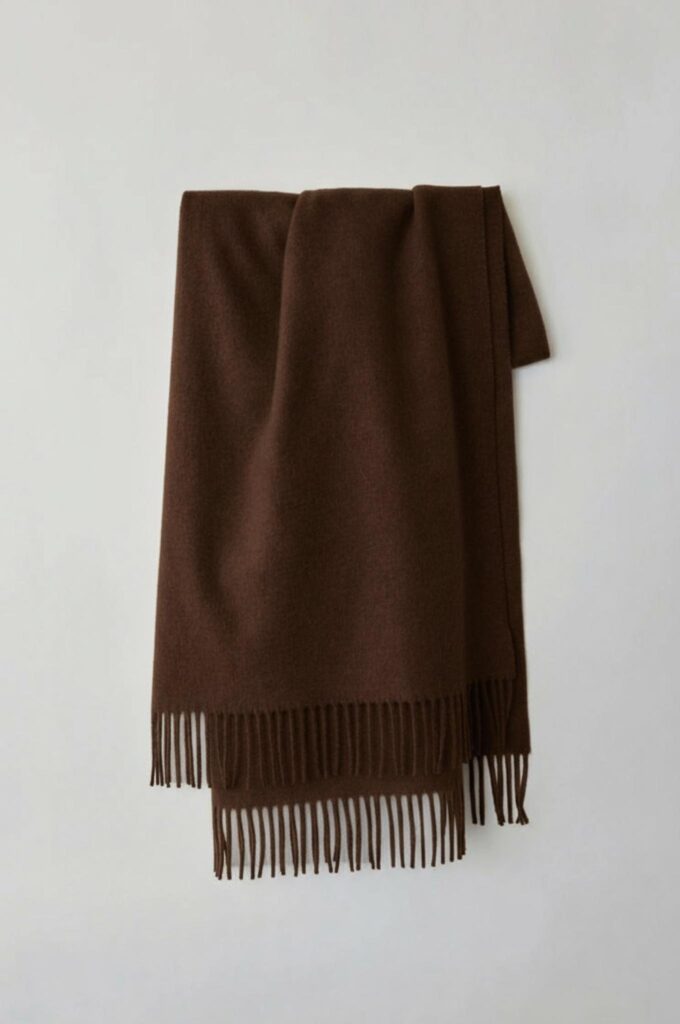 Chocolate brown fringed scarf displayed in the same controlled composition with preserved fabric texture and shadows.