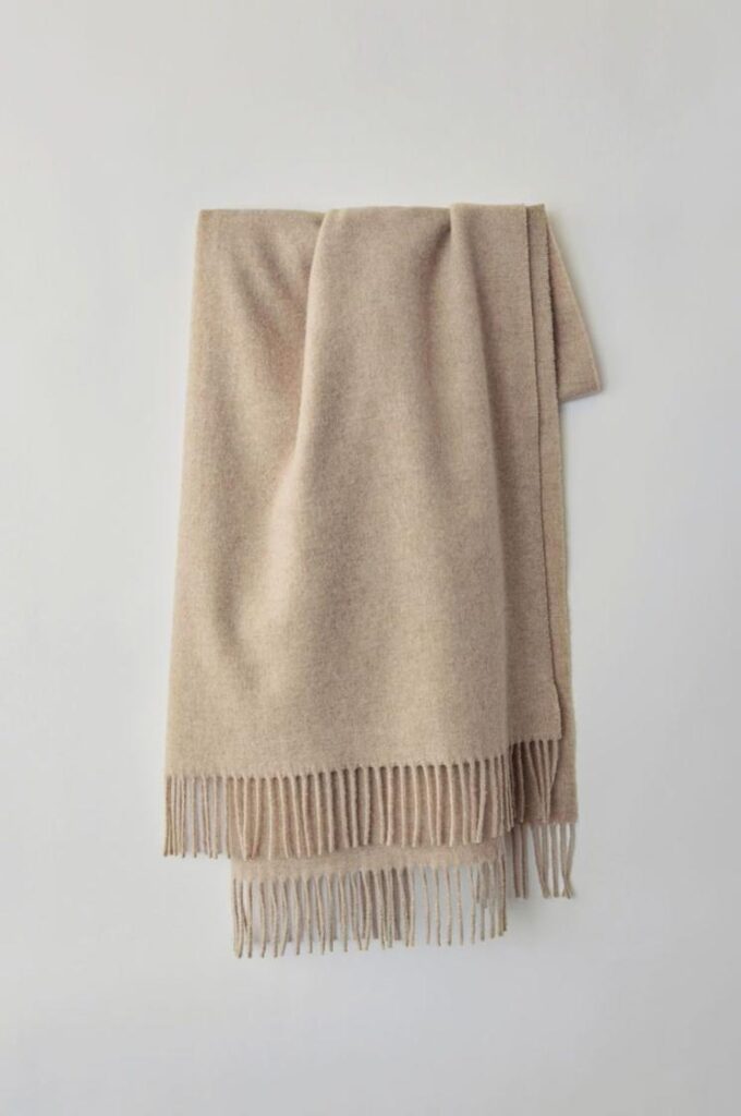 Original fringed scarf displayed against a clean light wall for controlled product color testing.