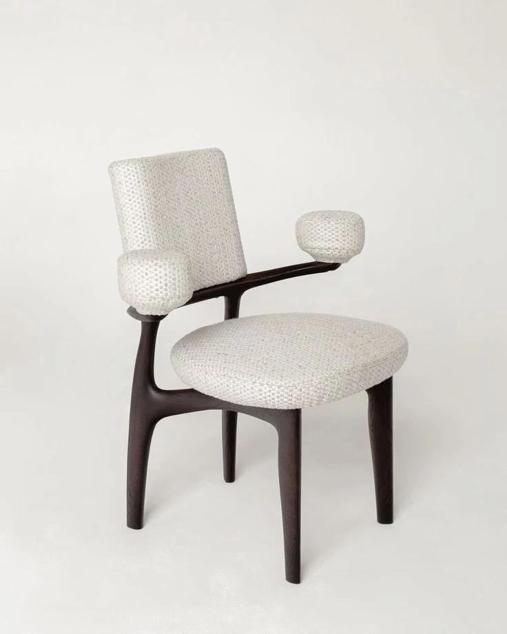 White upholstered accent chair with a dark wooden frame photographed against a simple studio background.