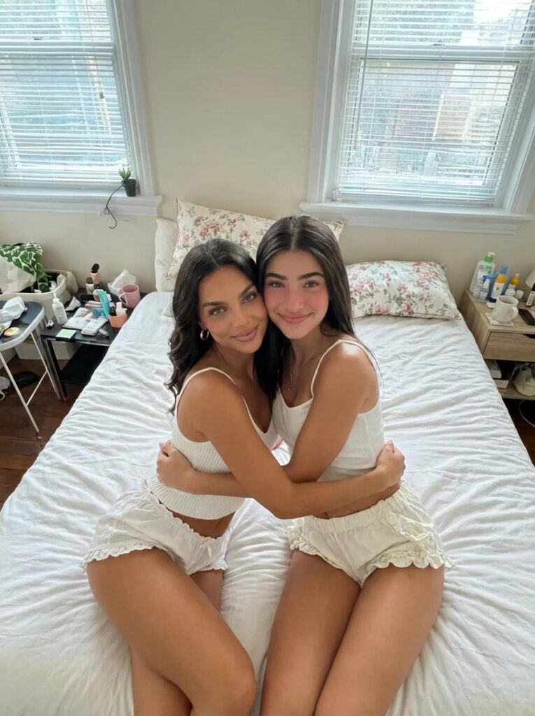 AI Image Combiner result showing two adult women sitting together on the same bed in a natural bedroom photo.