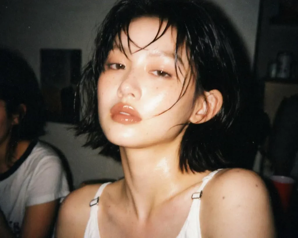Short-haired woman in a white top transformed into a candid flash-lit indoor photo.
