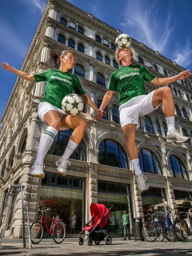 cupe – WeShop AI Blog Two football players juggling soccer balls in front of a city building.