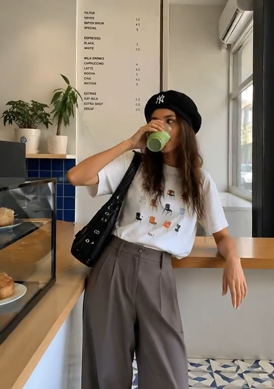 Woman drinking a green beverage in a café as the reference image for a 3D Cartoon Generator.