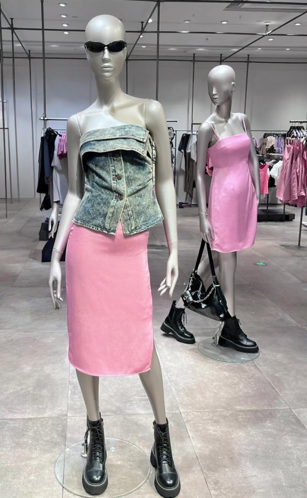 met – WeShop AI Blog Store mannequin wearing a denim top and pink skirt with another mannequin and accessories cluttering the background.